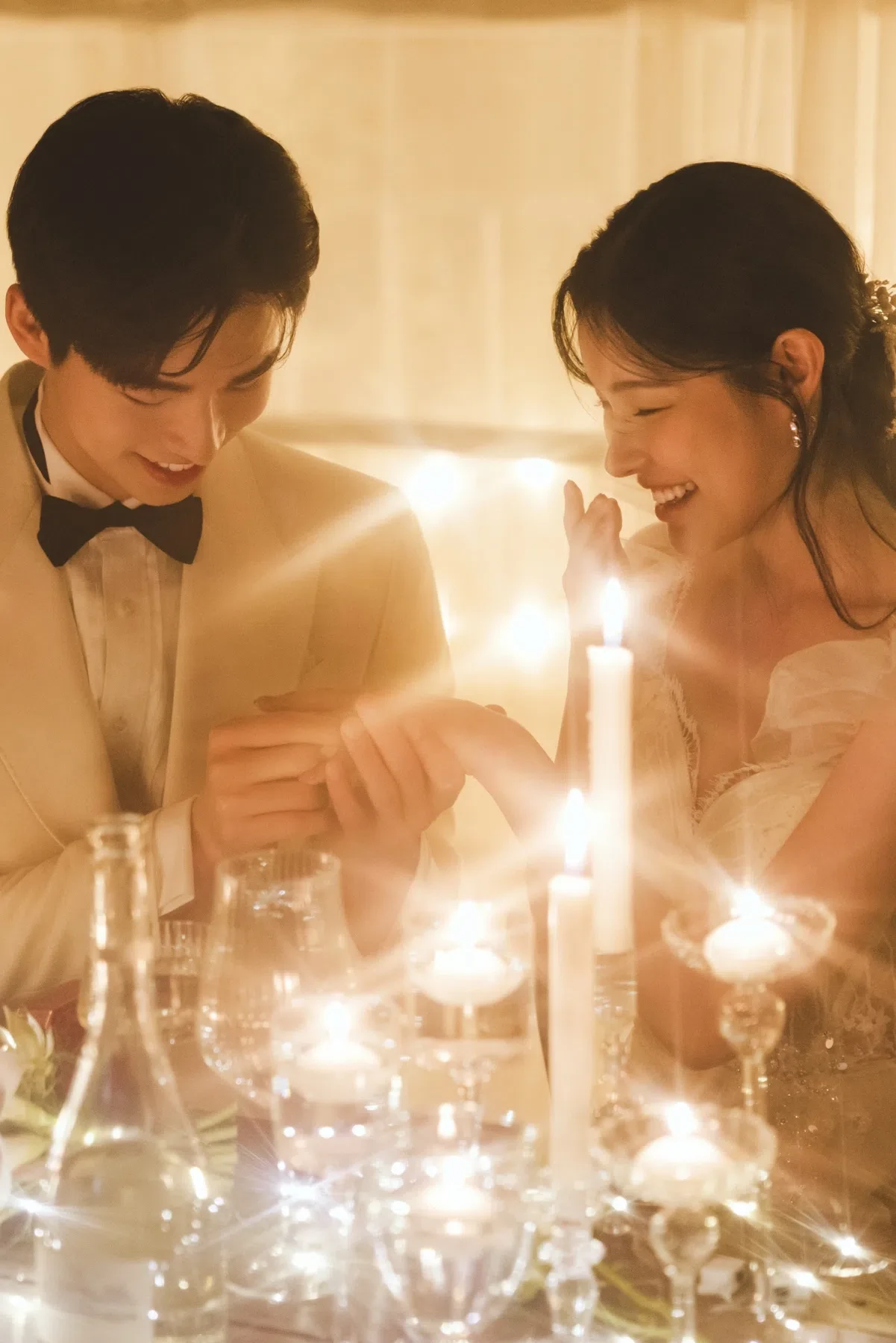 촛불이 놓인 실내 테이블의 자연광과 여백을 살린 커플 클로즈업입니다. 의상 실루엣과 표정 중심의 깨끗한 무드를 확인하기 좋습니다.