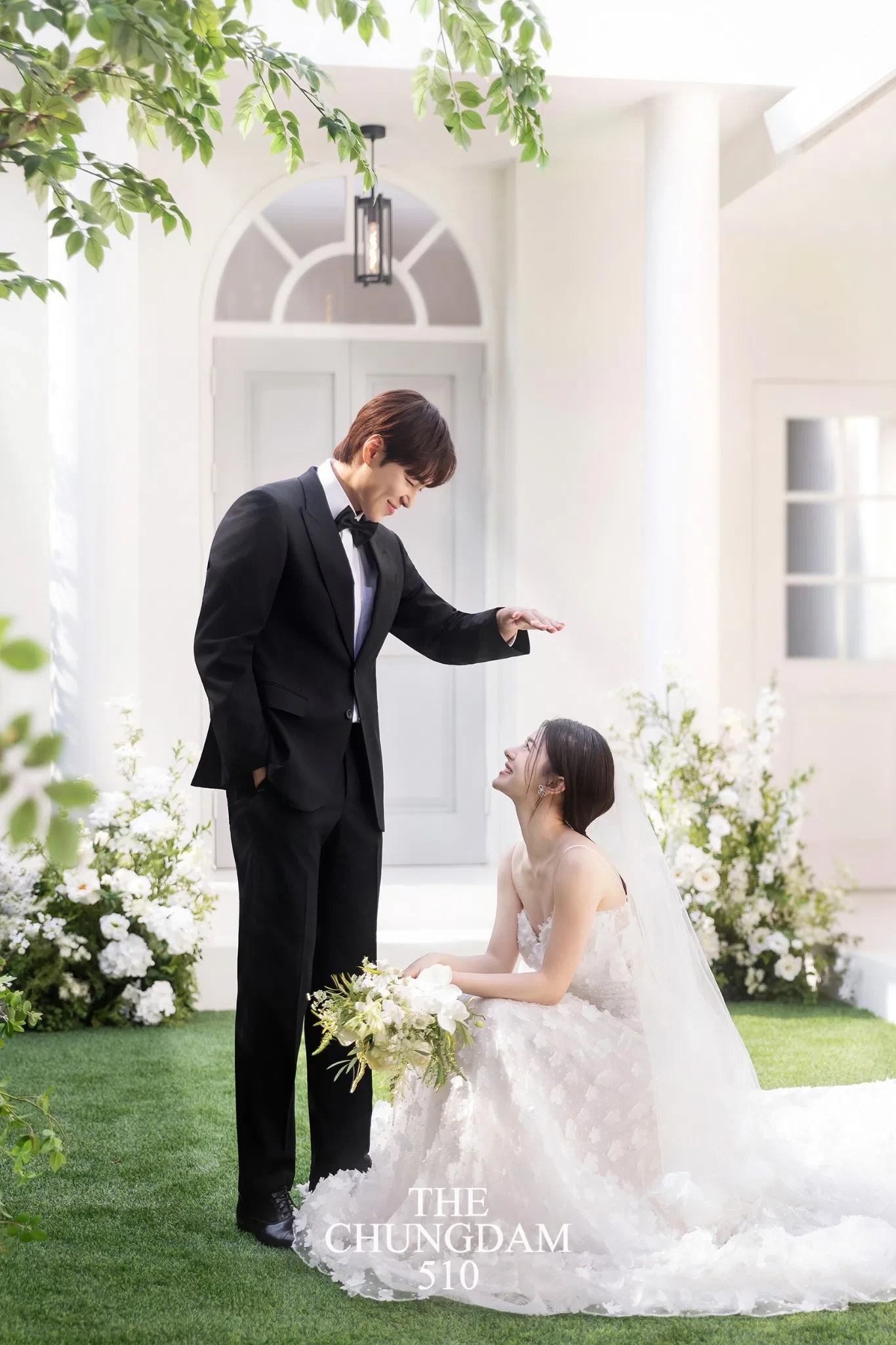 가든과 플로럴 배경이 드레스 실루엣을 부드럽게 감싸, 밝고 로맨틱한 내추럴 무드를 보여주는 컷입니다.