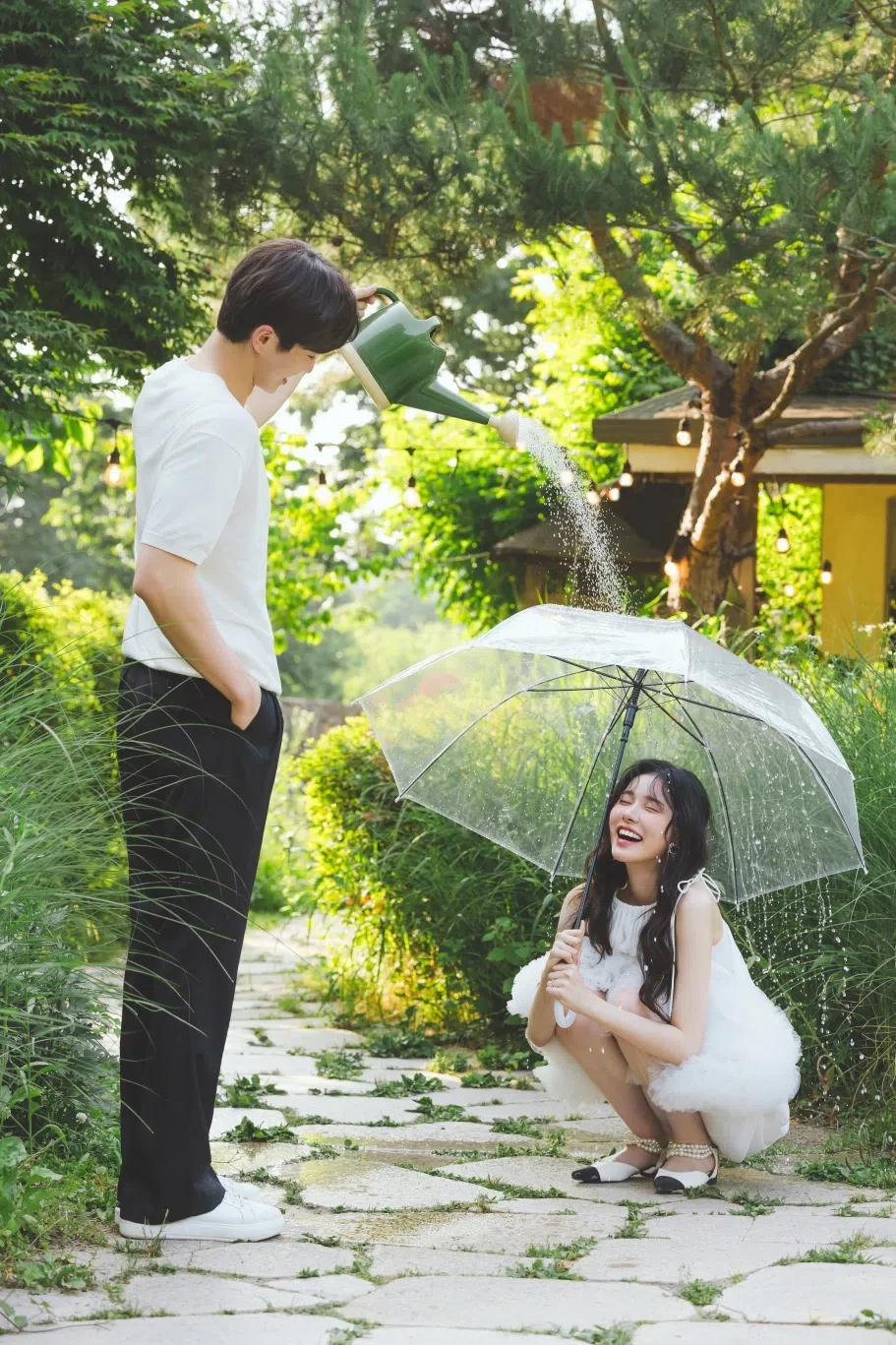 정원 산책로의 계절감과 동선을 살린 경쾌한 연출 컷입니다. 자연스러운 움직임과 초록 배경을 원하는 커플에게 어울립니다.