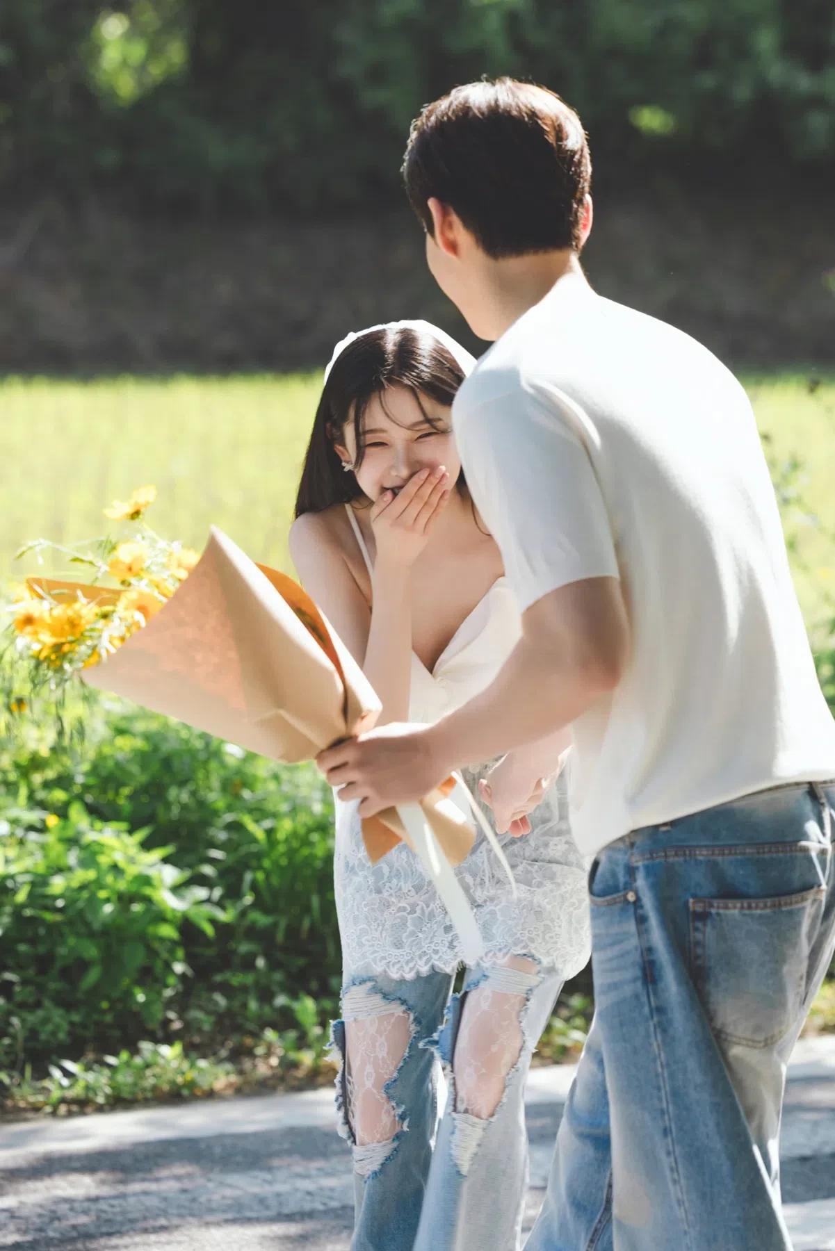 나무가 이어진 도로의 계절감과 동선을 살린 라이프스타일 커플 컷입니다. 자연스러운 움직임과 초록 배경을 원하는 커플에게 어울립니다.