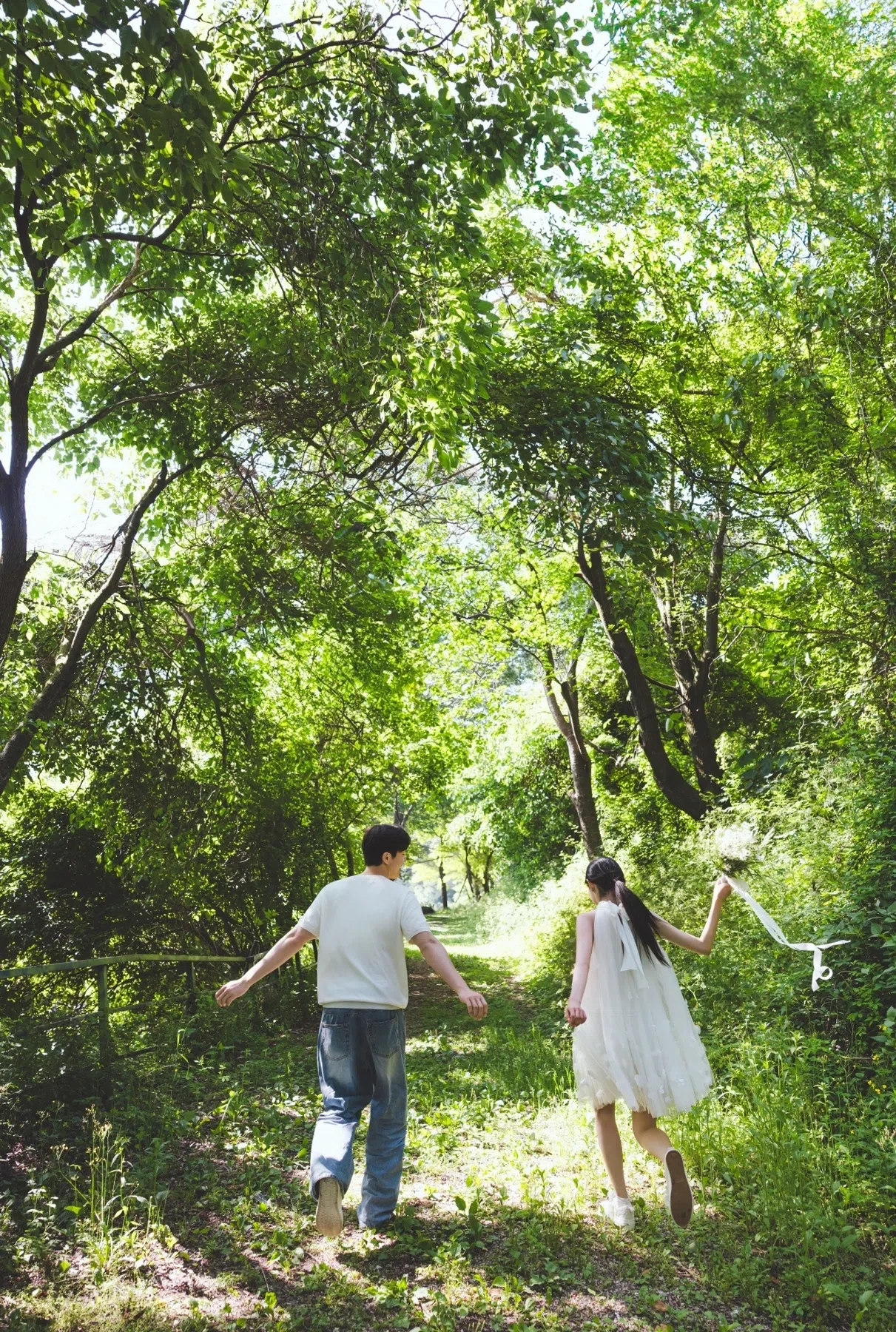 숲길의 계절감과 동선을 살린 야외 스토리 컷입니다. 자연스러운 움직임과 초록 배경을 원하는 커플에게 어울립니다.
