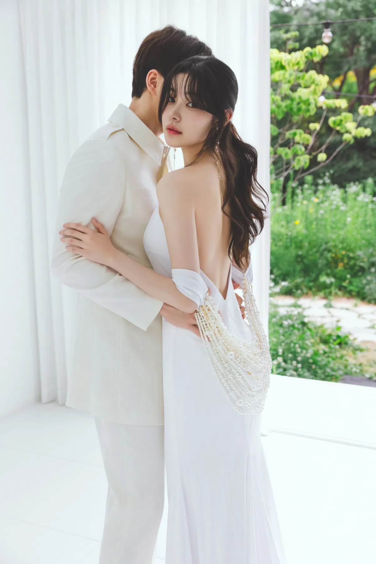 화이트 창가의 자연광과 여백을 살린 커플 클로즈업입니다. 의상 실루엣과 표정 중심의 깨끗한 무드를 확인하기 좋습니다.