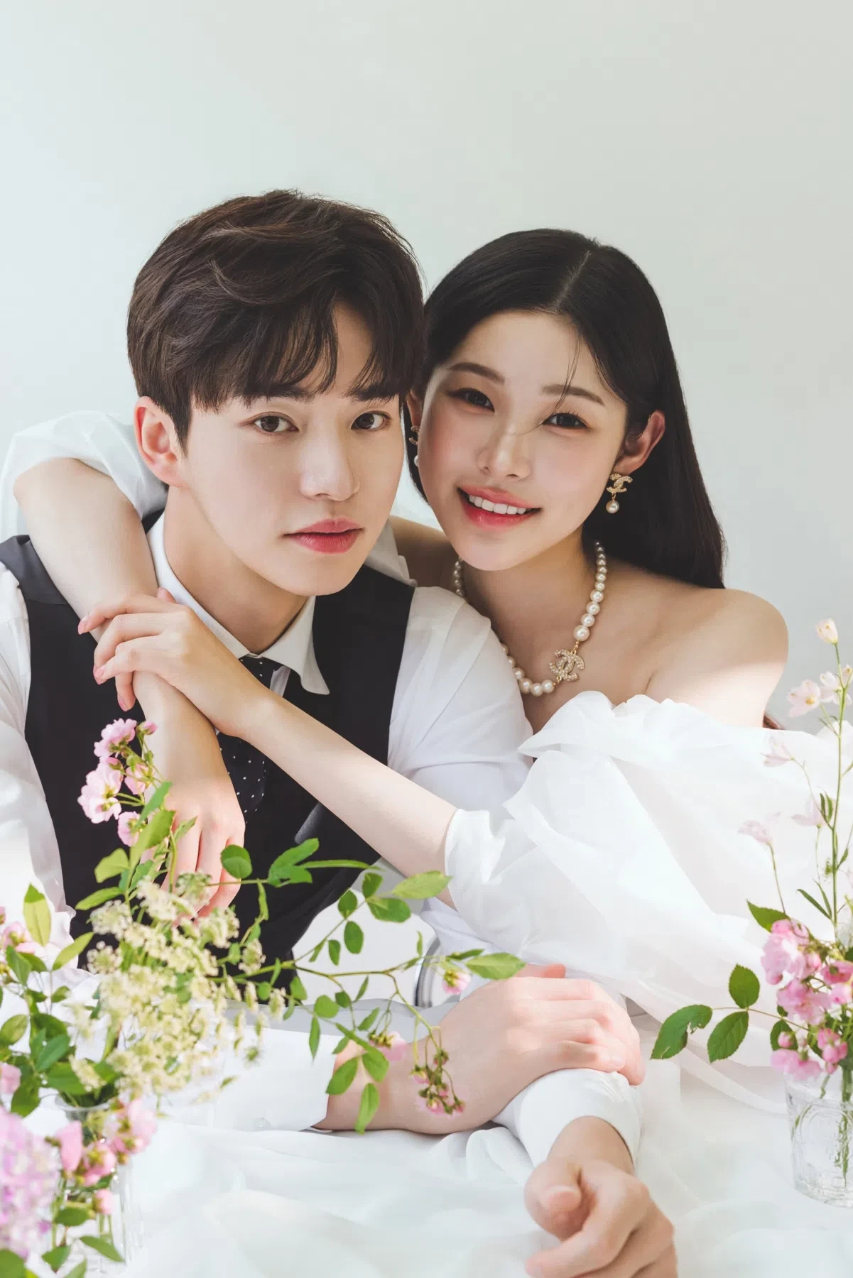 화이트 테이블 플라워 세트의 자연광과 여백을 살린 커플 클로즈업입니다. 의상 실루엣과 표정 중심의 깨끗한 무드를 확인하기 좋습니다.