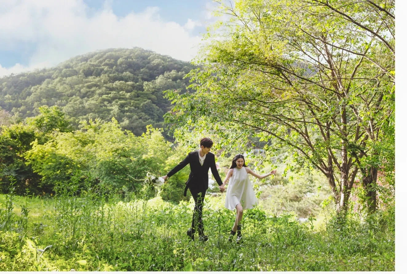 mountain meadow의 계절감과 동선을 살린 야외 스토리 컷입니다. 자연스러운 움직임과 초록 배경을 원하는 커플에게 어울립니다.