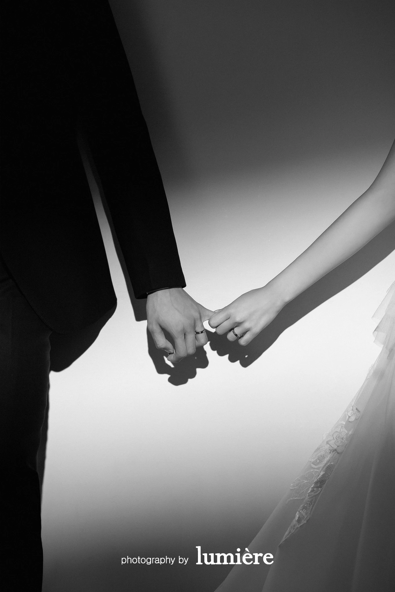단색 배경의 실내 세트에서 남녀의 손 디테일이 서로 손가락을 걸고 있음 모습이다. 손·반지가 함께 보인다.