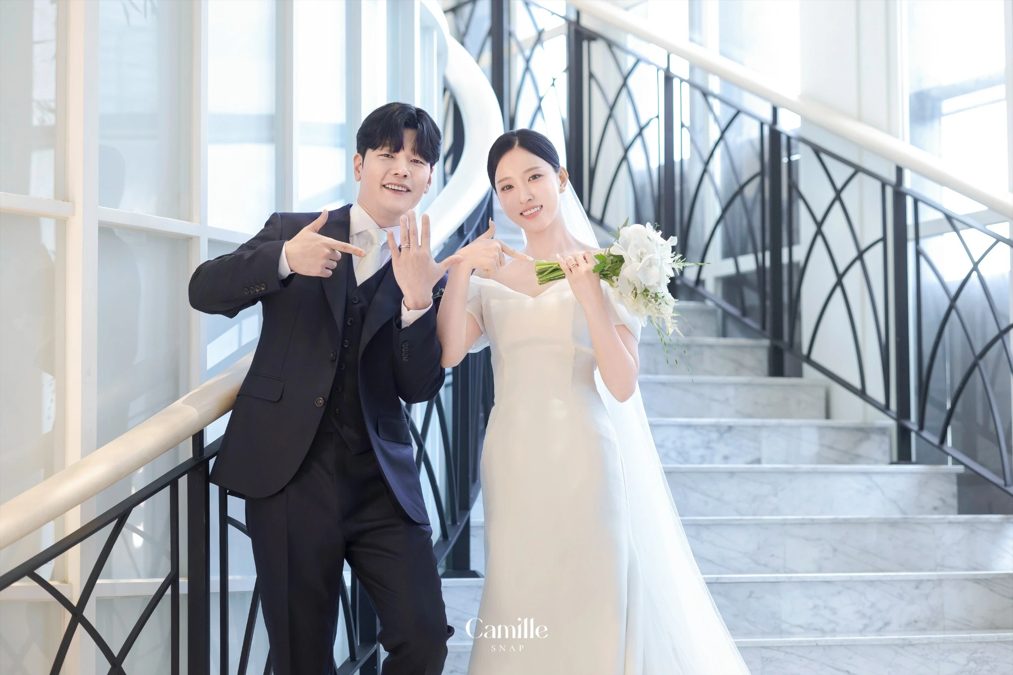 밝은 계단 공간에서 신랑신부의 가벼운 포즈를 담은 컷입니다.