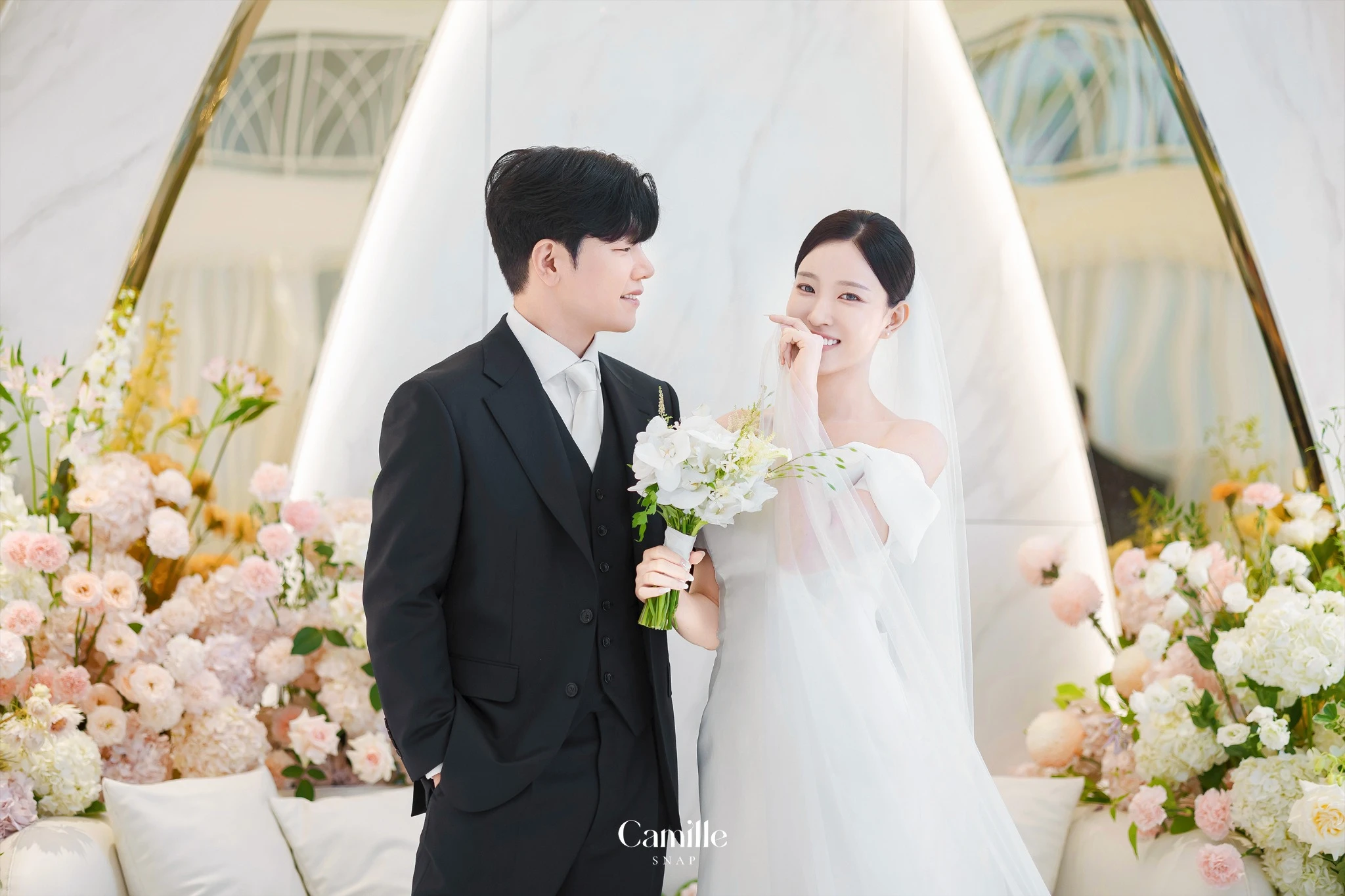 신랑신부의 가까운 표정과 부케가 함께 보이는 커플 컷입니다.