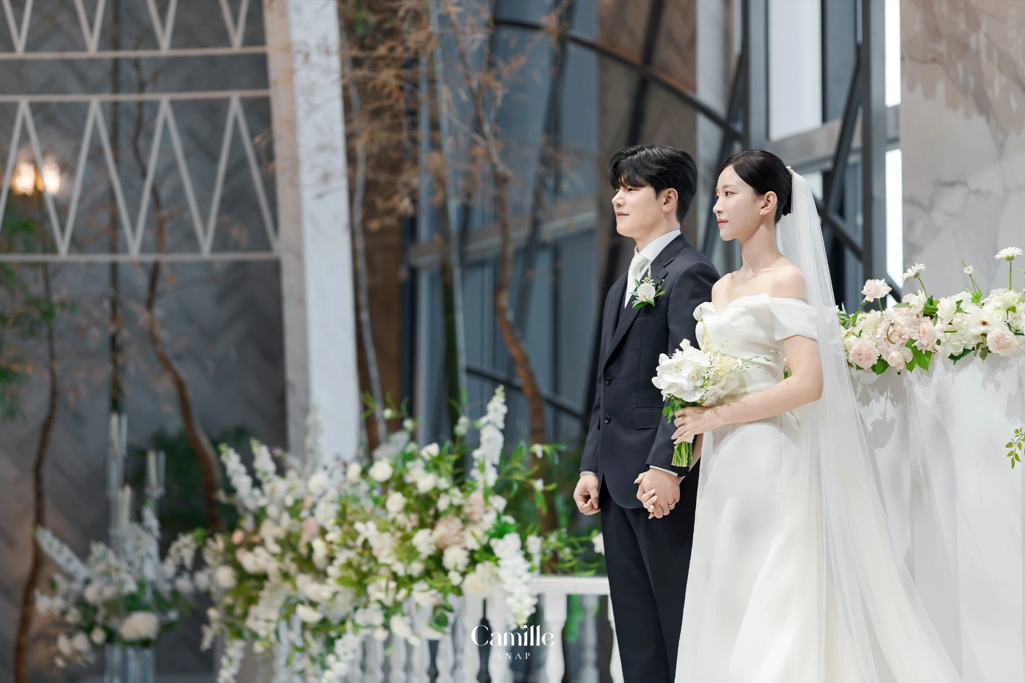 예식 공간의 장식과 신랑신부의 정돈된 자세가 함께 보이는 컷입니다.