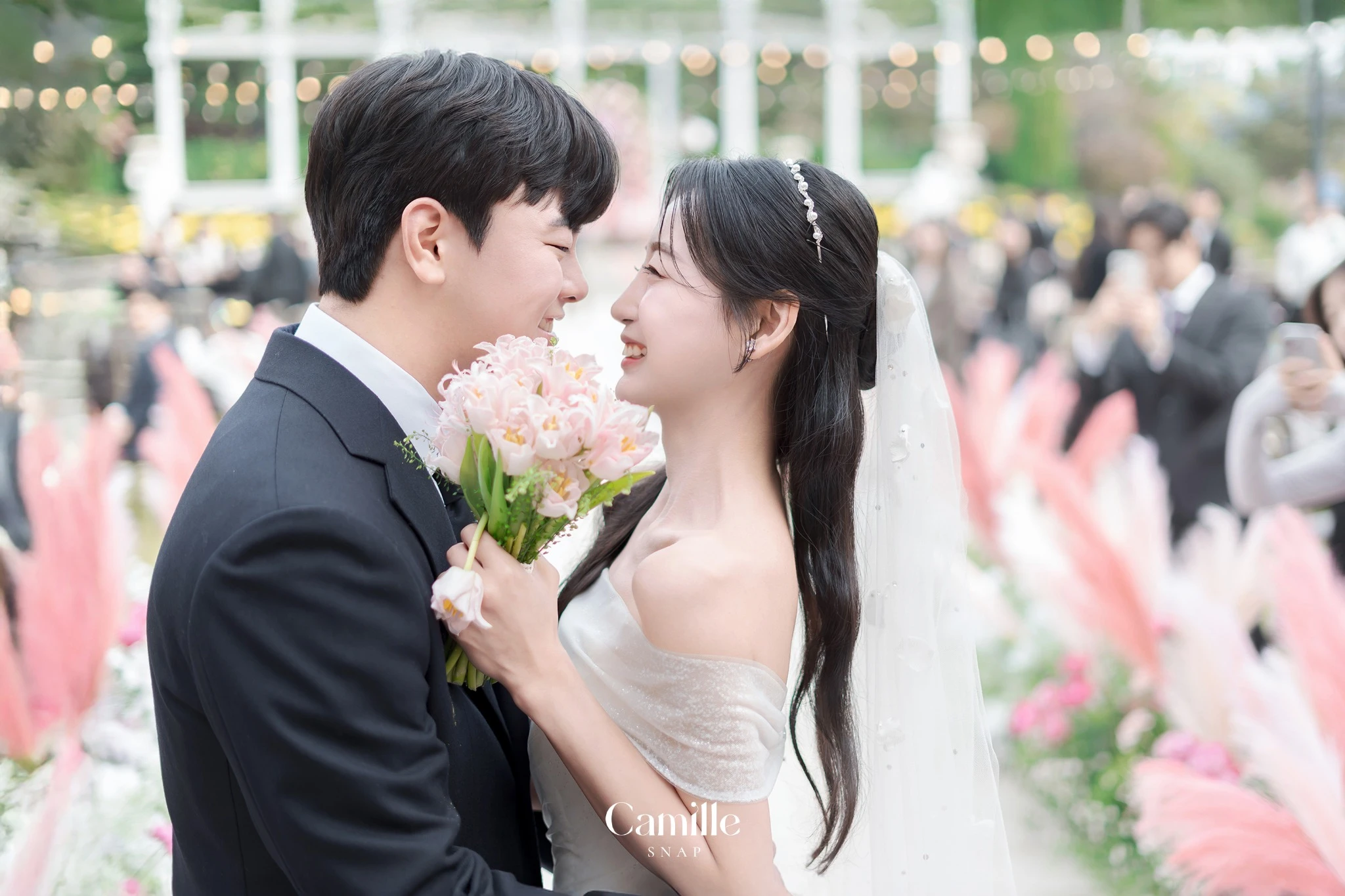 신랑신부의 밝은 표정과 부케가 중심이 되는 클로즈업 컷입니다.
