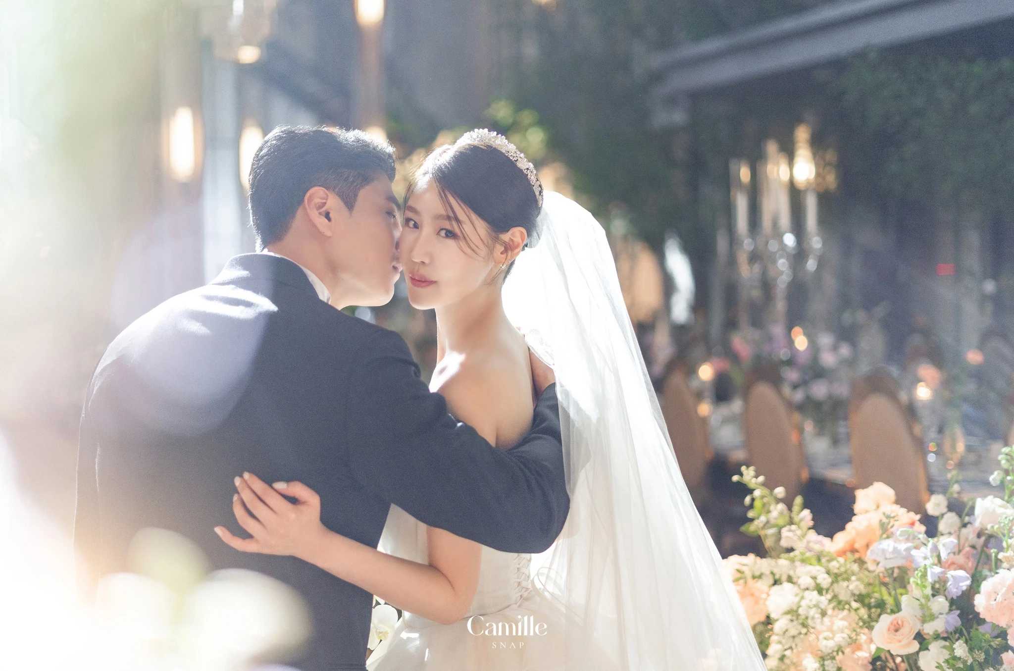 부드러운 역광과 베일이 신랑신부의 가까운 순간을 감싸는 컷입니다.