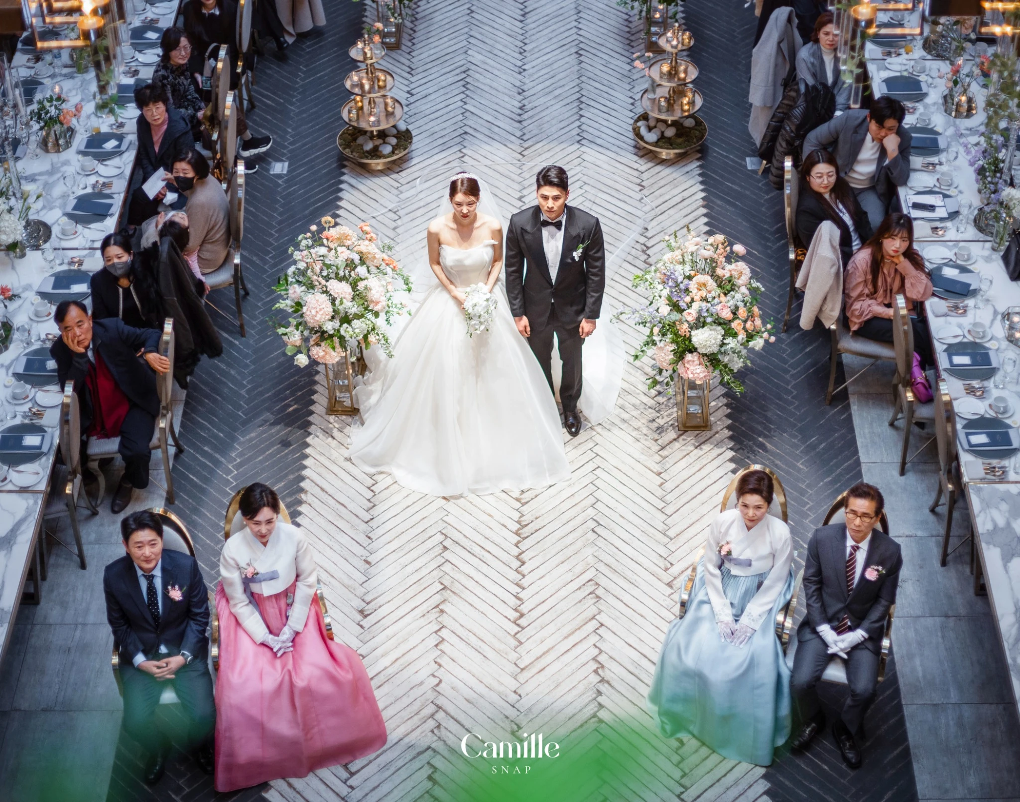 예식장 중앙의 인물 배치와 주변 하객석을 위에서 담은 컷입니다.