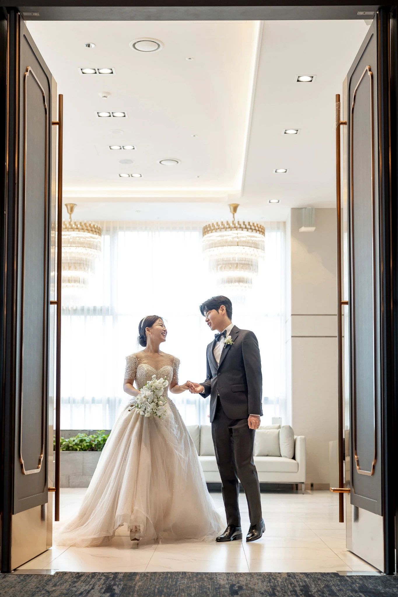 커플 입맞춤 장면으로, 아치형 창과 꽃 장식이 있는 밝은 실내와 아치형 창와 베일가 함께 보이는 장면입니다.