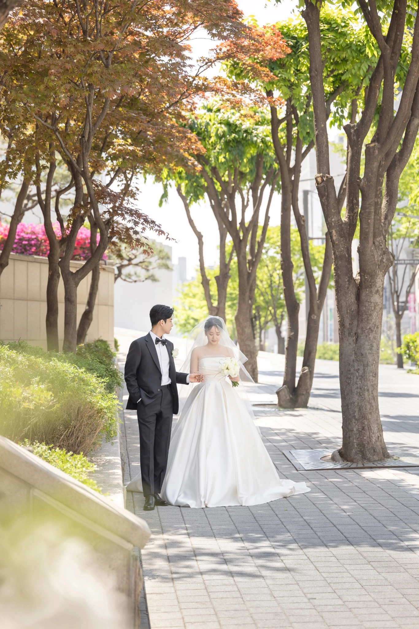 꽃 장식 클로즈 커플 컷으로, 꽃 아치와 베일이 둘러싼 가까운 좌석 공간와 베일와 부케가 함께 보이는 장면입니다.