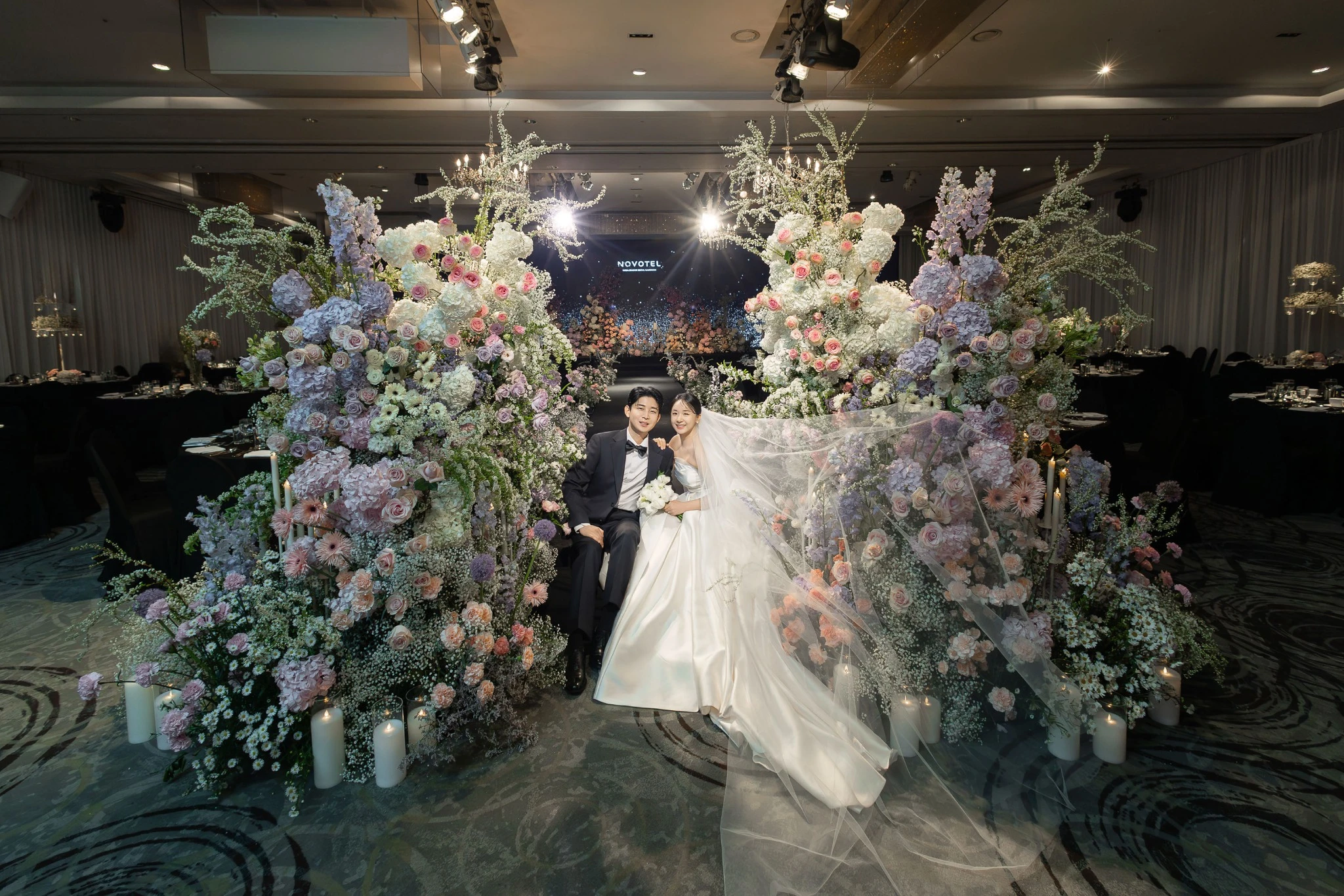 입장·행진 장면으로, 밝은 예식홀 버진로드와 하객석와 하객와 꽃길가 함께 보이는 장면입니다.