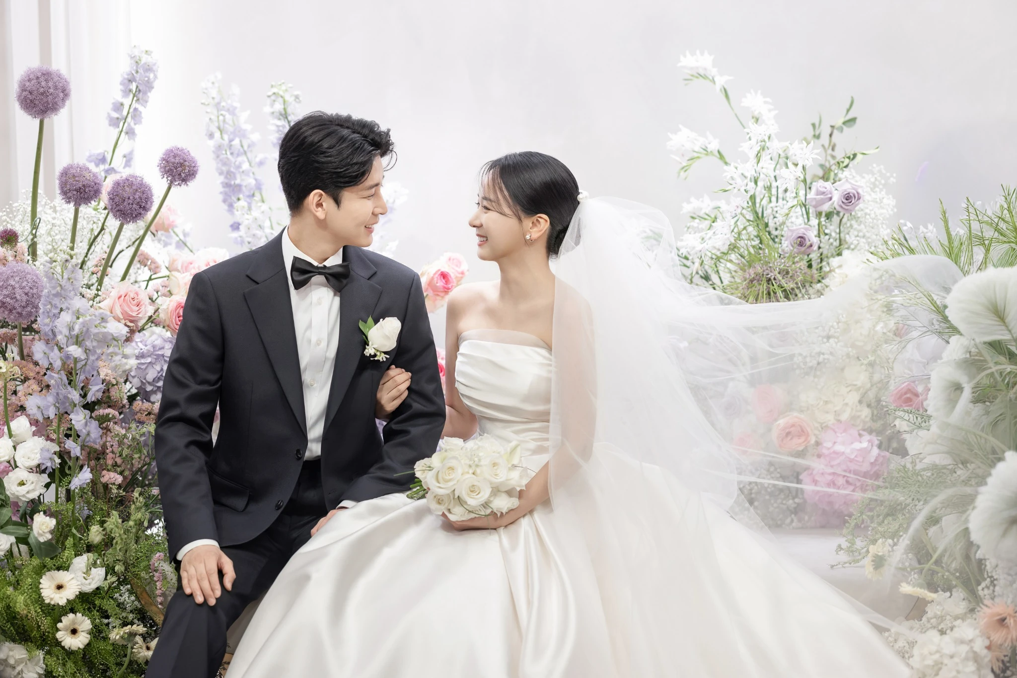 반지 공개 인물 컷으로, 밝은 연회홀과 하객석와 반지과 부케가 함께 보이는 장면입니다. 공개 갤러리에서 장면 설명용으로 사용할 수 있습니다.