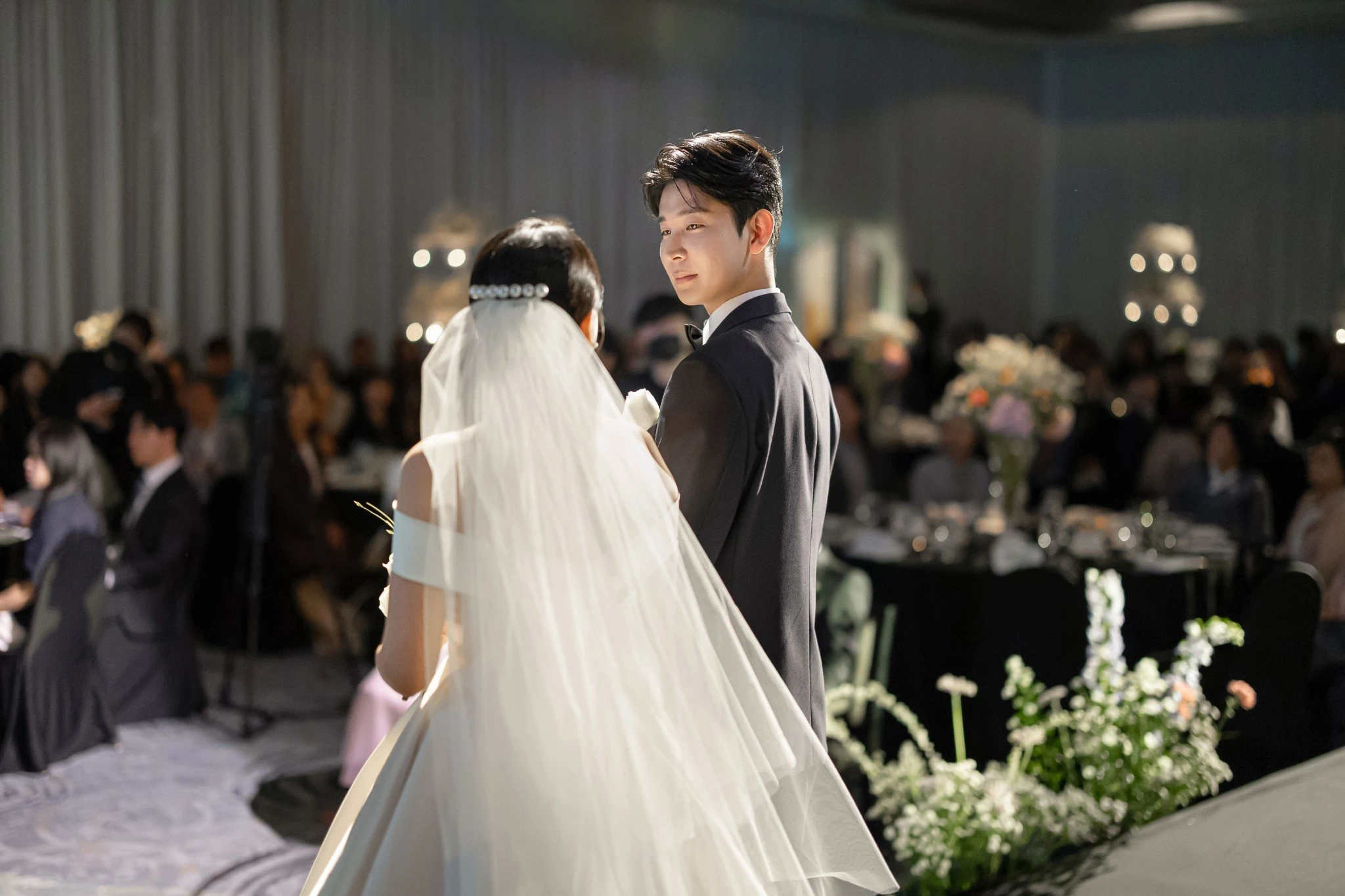 대형 베일 연출 전경으로, 넓은 예식홀 버진로드와 긴 베일와 샹들리에가 함께 보이는 장면입니다.