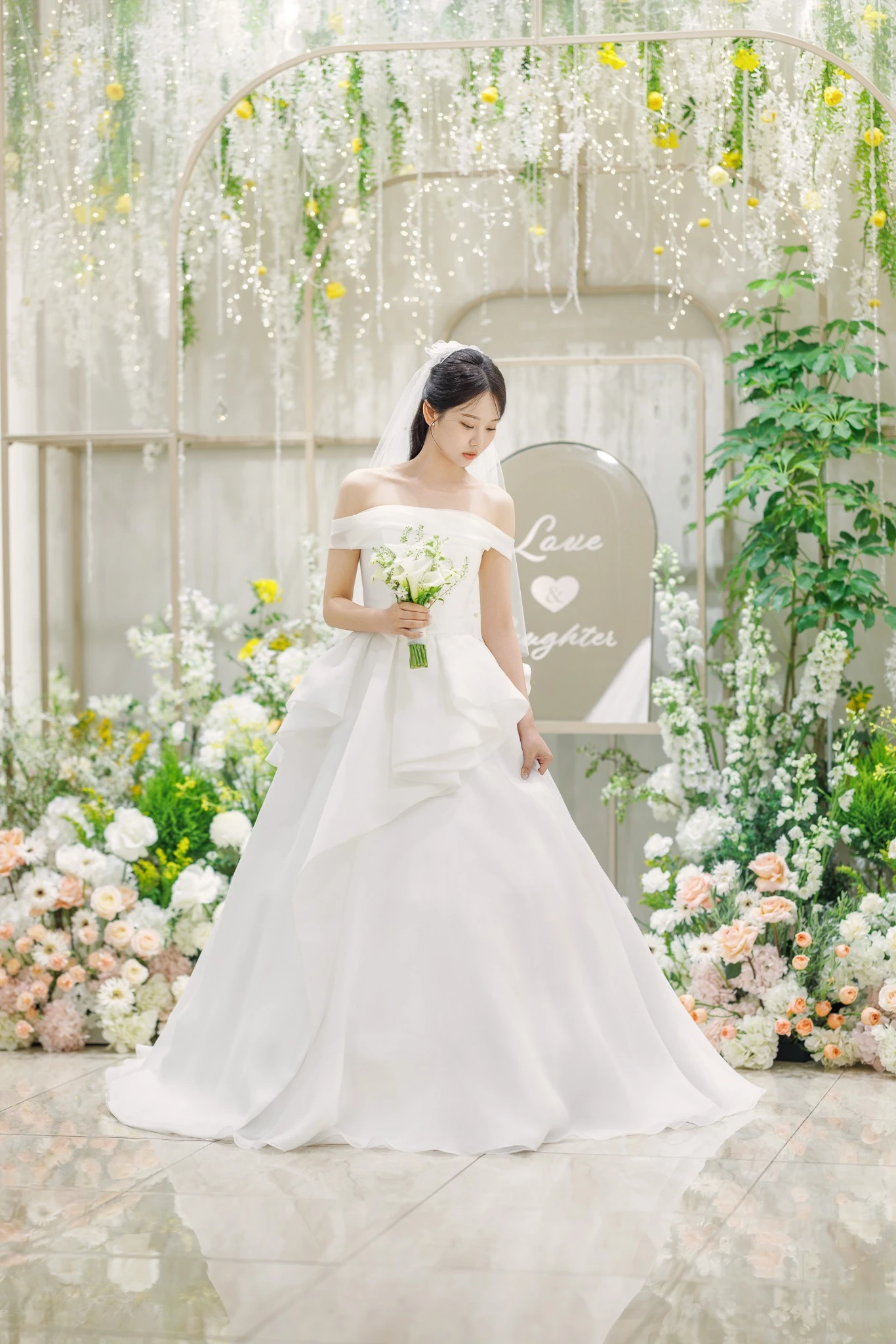 로비 베일 연출 컷으로, 거울 천장과 목재 문이 있는 밝은 로비와 거울 천장와 목재 문가 함께 보이는 장면입니다.