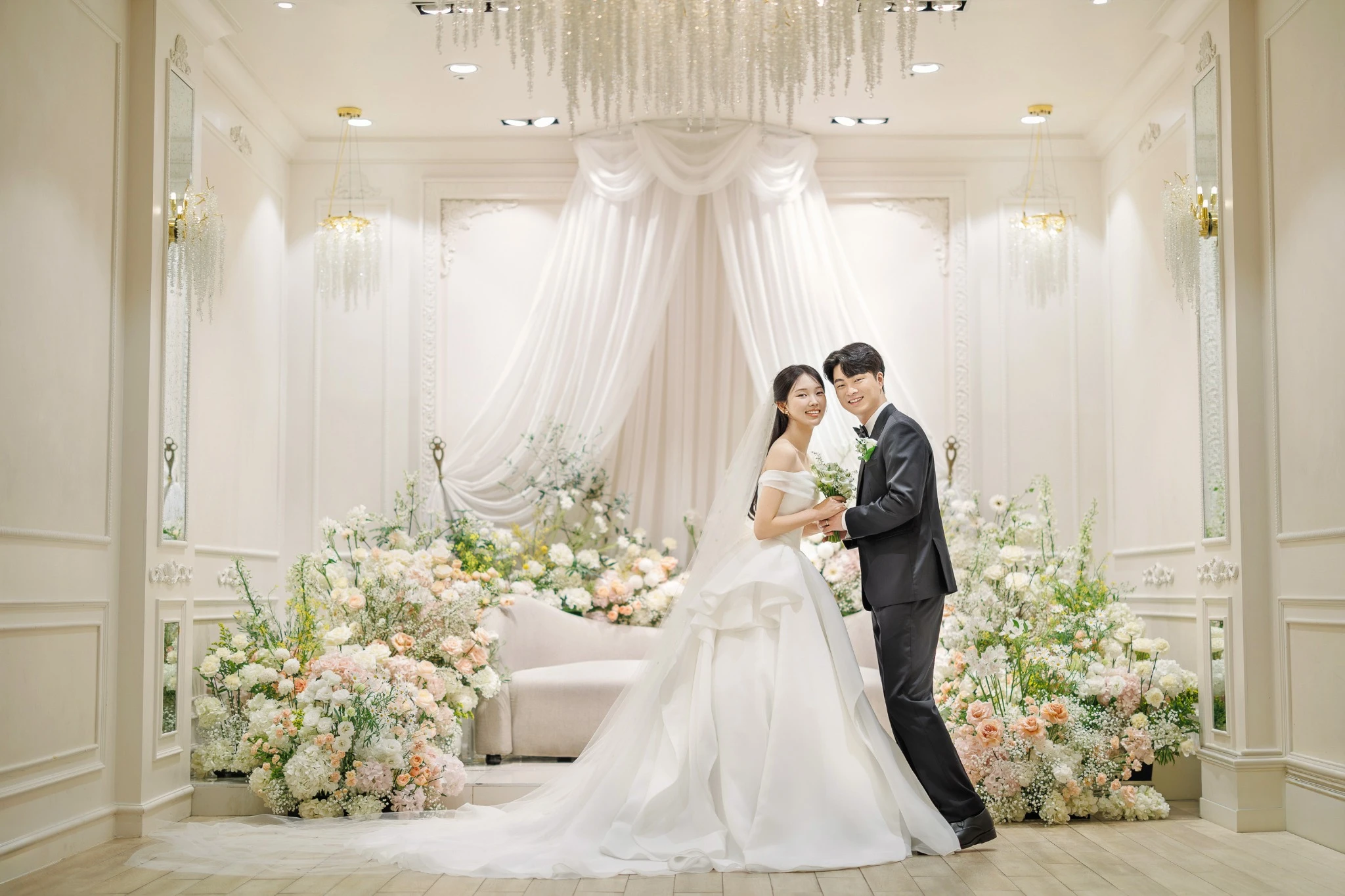 버진로드 커플 컷으로, 밝은 꽃길과 촛불 장식이 있는 홀와 부케과 촛불가 함께 보이는 장면입니다.