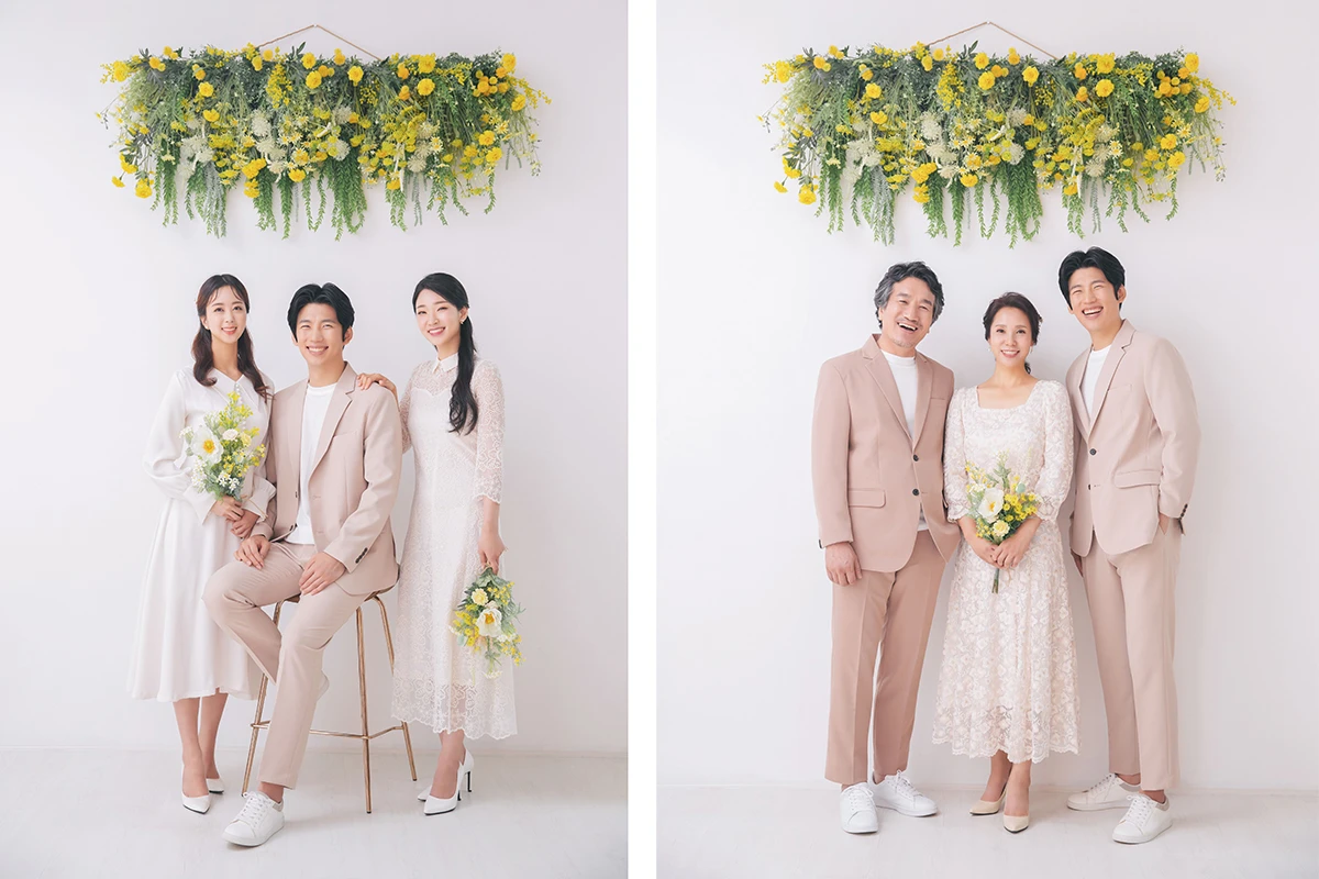 회색 스튜디오 배경의 흑백 사진에서 턱시도와 드레스를 입은 성인 5명이 회색 배경 앞 흑백 톤으로 배치된 사진이며, 의자와 긴 드레스가 장면의 구성을 보완합니다.