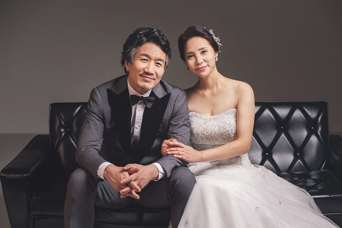 밝은 흰색 스튜디오에서 베이지 정장과 흰 원피스 차림의 성인 3명이 흰 배경과 노란 꽃 장식 아래 배치된 분할 사진이며, 노란 꽃 장식과 부케가 장면의 구성을 보완합니다.